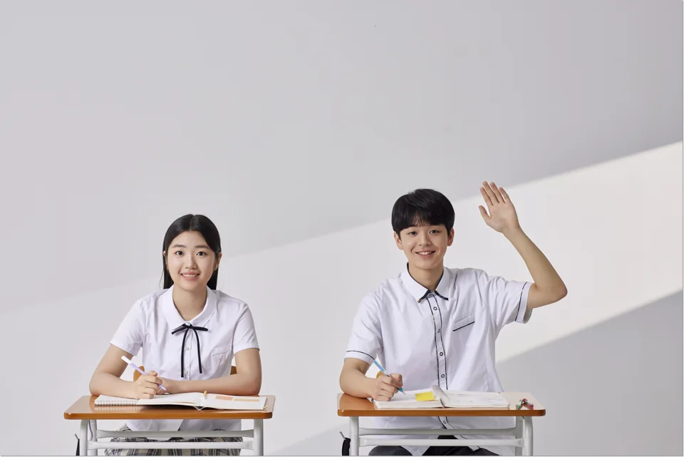 책상에 앉아 손을 든 학생들