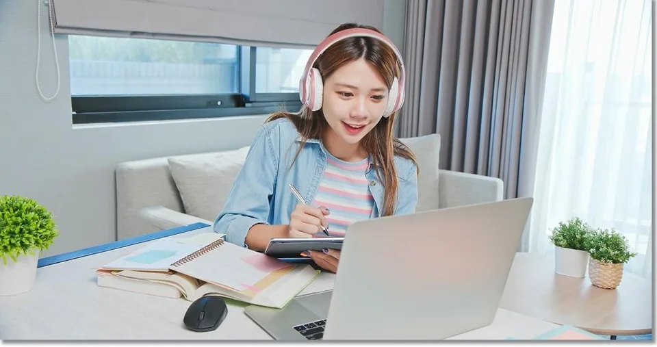 노트북 앞에서 공책에 쓰는 모습