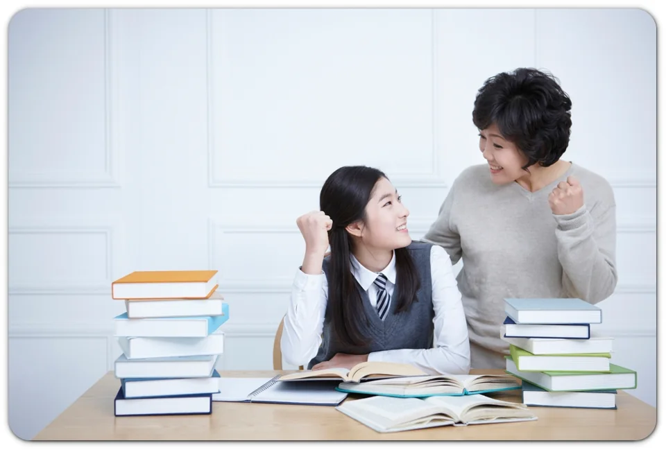 두 학생이 교재를 보며 이야기하는 모습