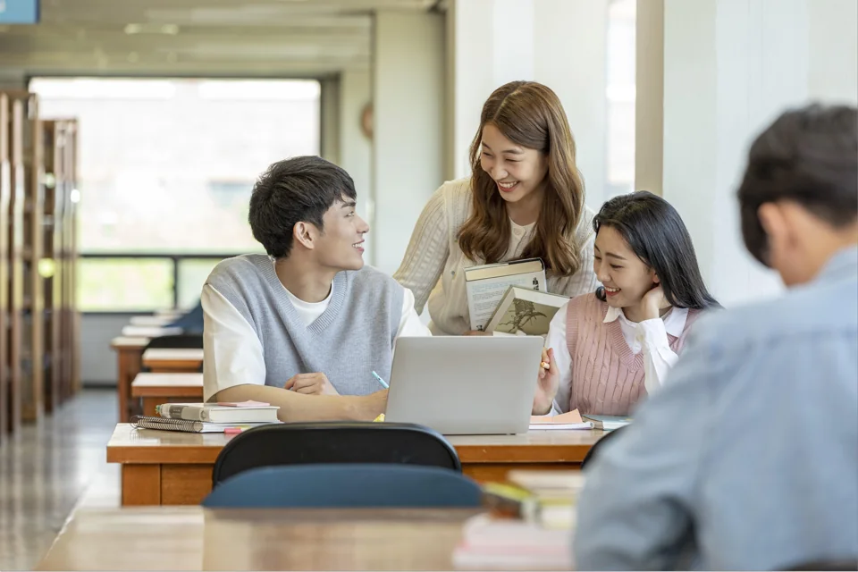 선생님과 책을 보며 대화하는 학생들